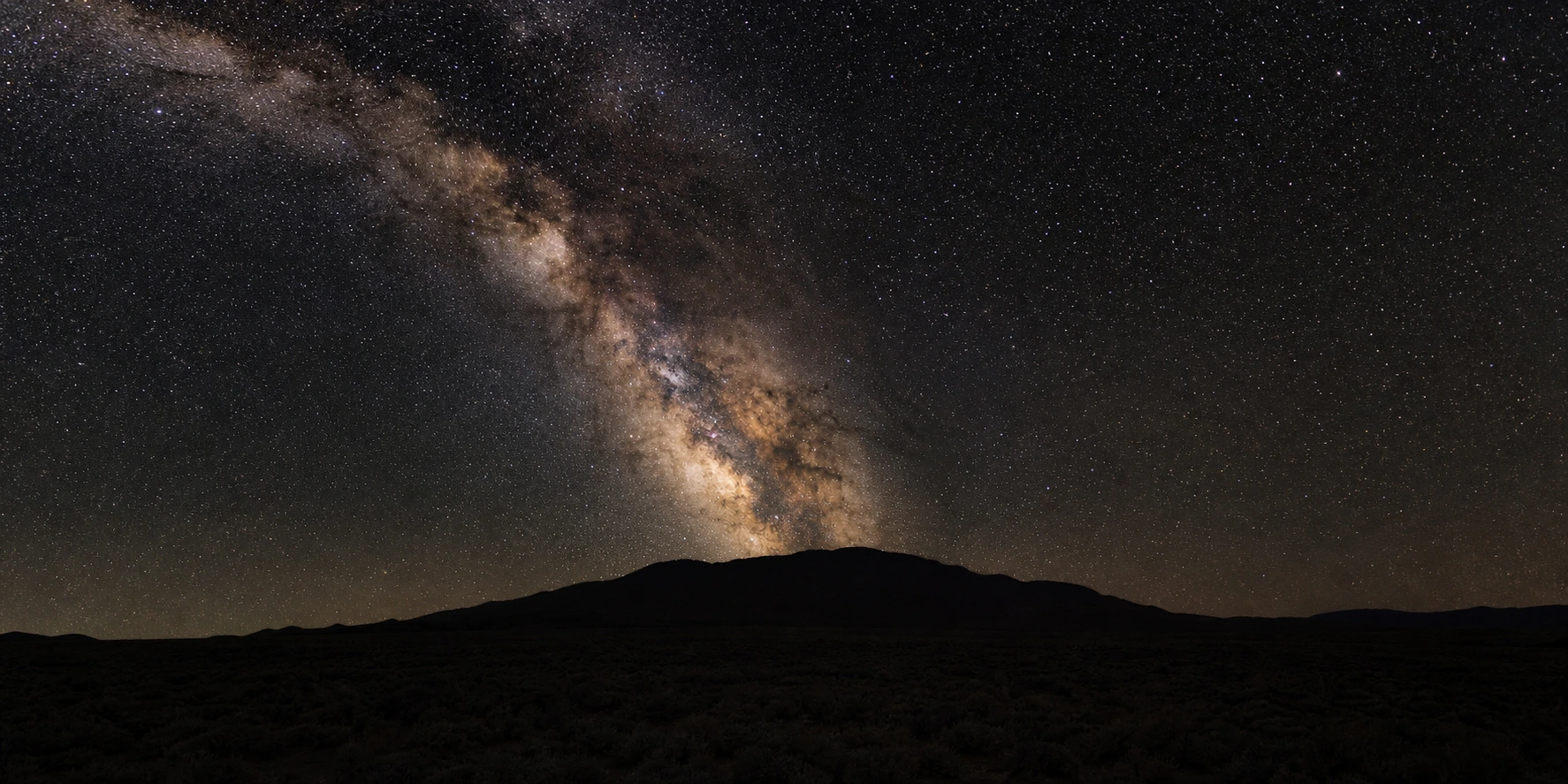 Long-exposure photo of the Milky Way galactic core over a dark desert ridge, representing share of model across AI engines